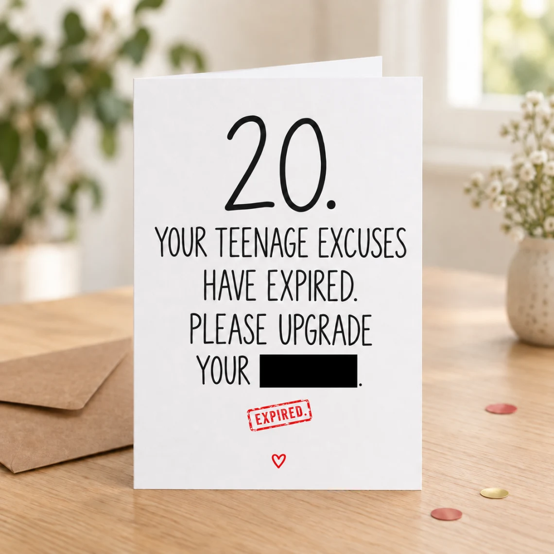Lifestyle mock-up of a standing 20th birthday card on a wooden table, with a kraft envelope and red/gold confetti. The teenage-excuses joke has one word covered by a black bar, above a red EXPIRED stamp.